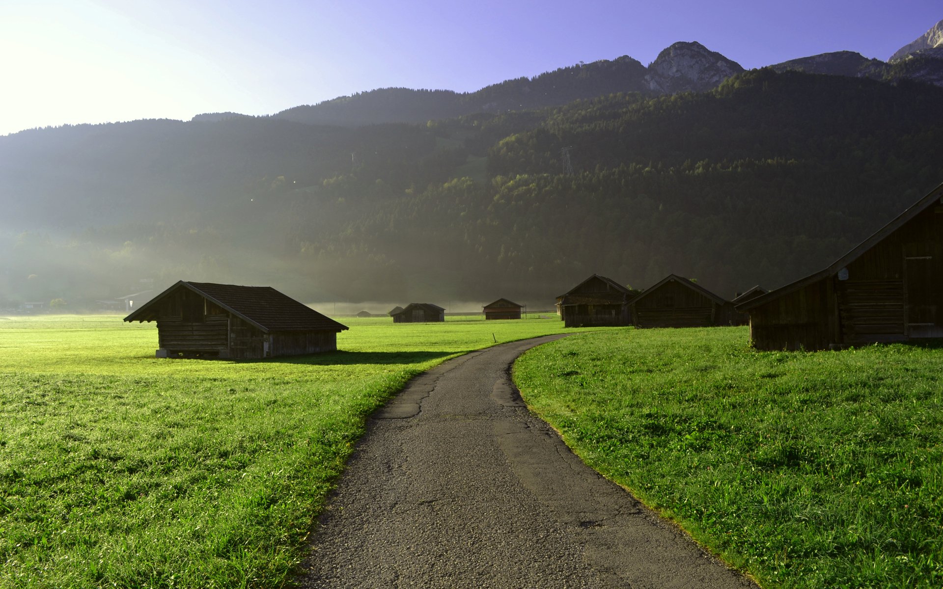 ebene felder spur weg asphalt häuser gras grün morgen morgendämmerung beginn des tages berge hügel wald bäume himmel ansicht