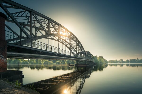 Pont arqué sur la rivière à l autre rive où le soleil brille