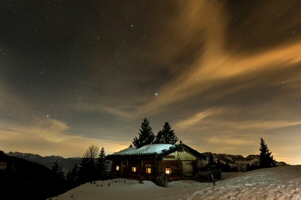 A house with burning windows in the snowy hills