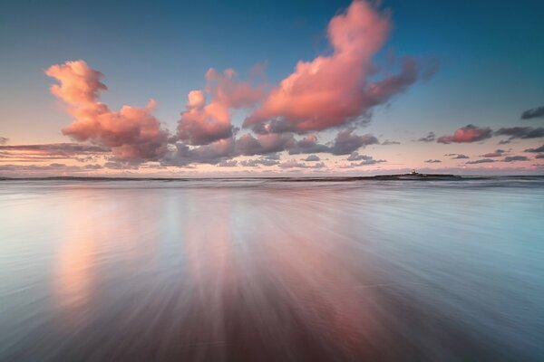 Les nuages roses se reflètent dans la surface de la mer