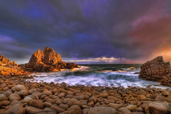 Surf nocturno en el océano. Rocas en la orilla