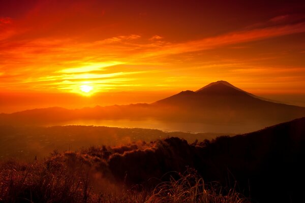 Orange Sonnenuntergang, der Berge umhüllt