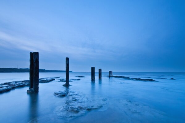 Holzsäulen am Meer am Abend