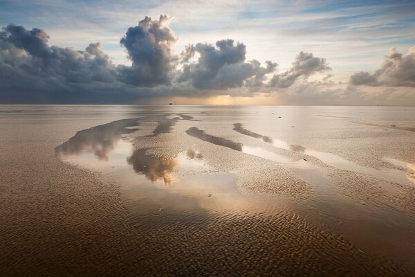 Tobende Wolken vor dem Hintergrund eines ruhigen Strandes