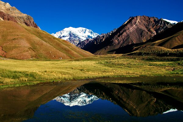 Lake on the background of mountains and grassy hills