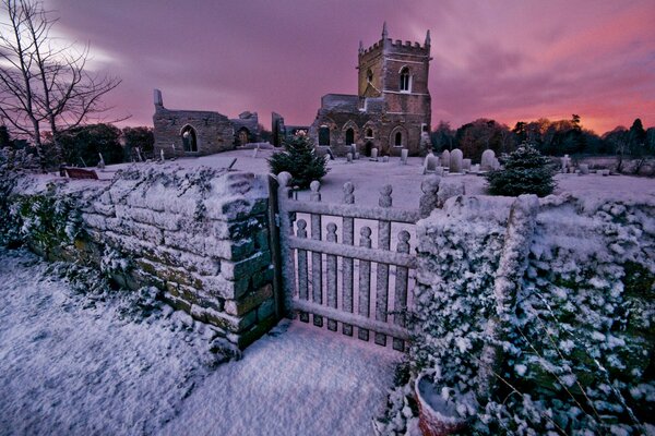 Église avec cimetière en hiver au coucher du soleil