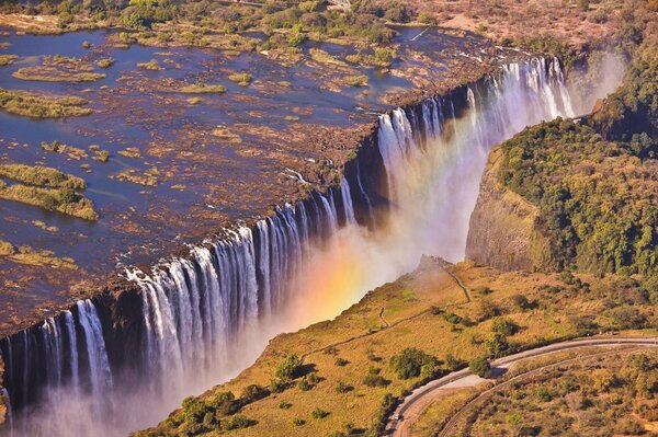 A waterfall in Zambia with a multicolored rainbow