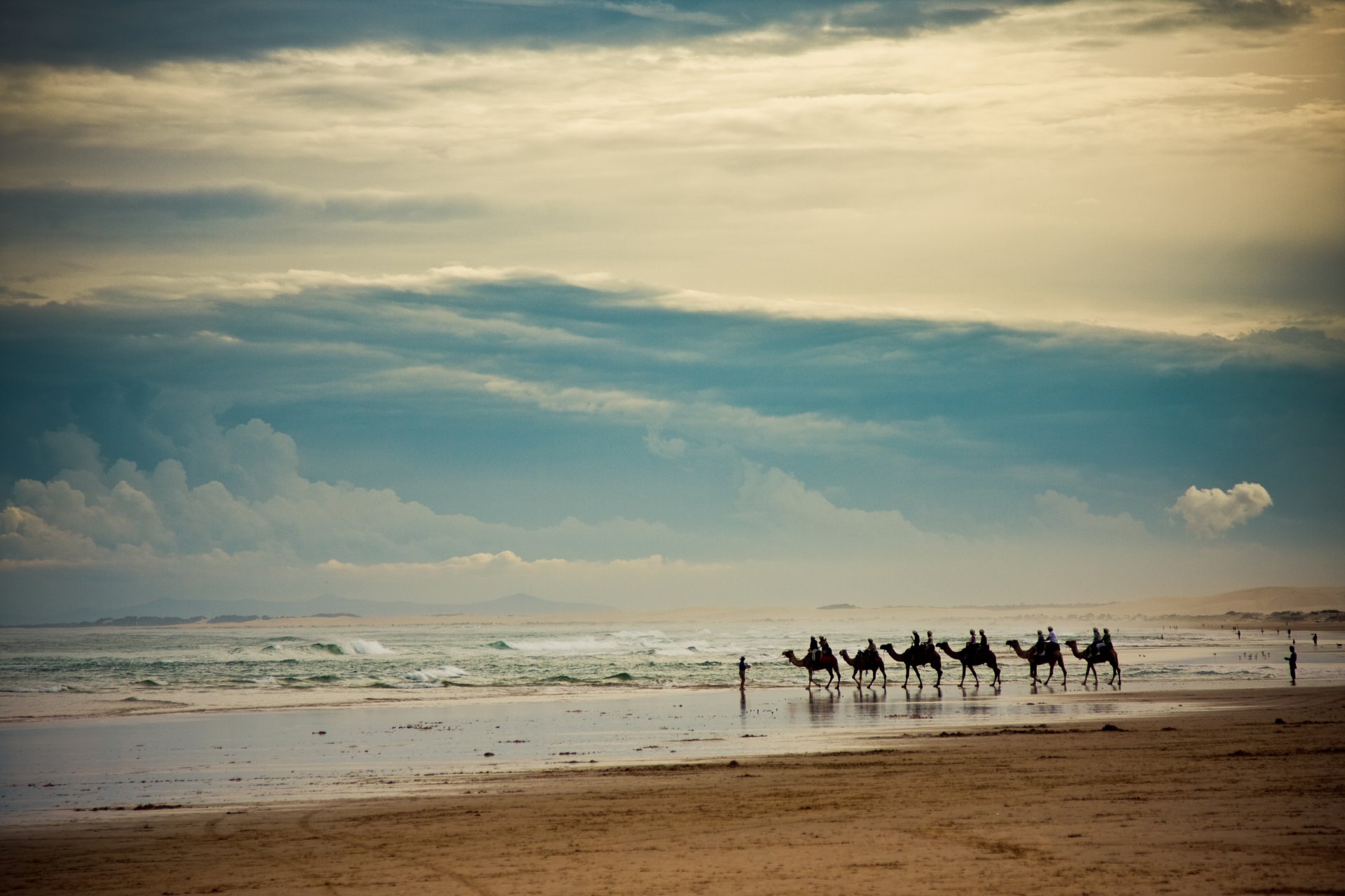 landscape sea waves sky clouds beach sand horizon people caravan camel