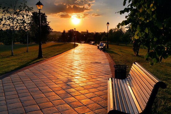 Parc avec des bancs sous le ciel nuageux du coucher du soleil