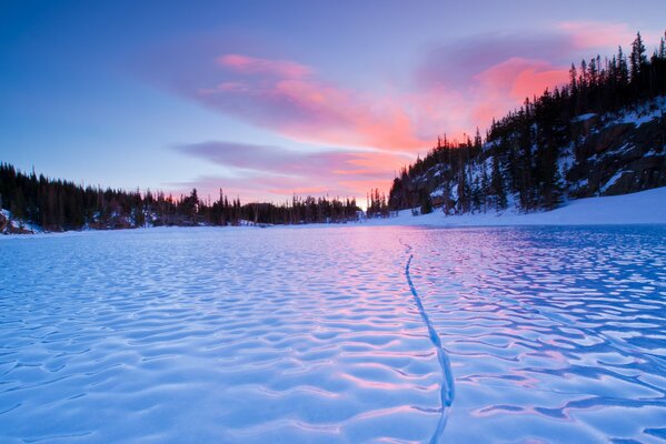 Ein Winterfluss mit bewaldeten Ufern, Bäume sind mit Schnee bedeckt