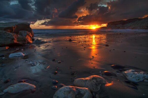 Dunkle Landschaft mit einem Meer aus Steinen, Wolken und Sonnenaufgang