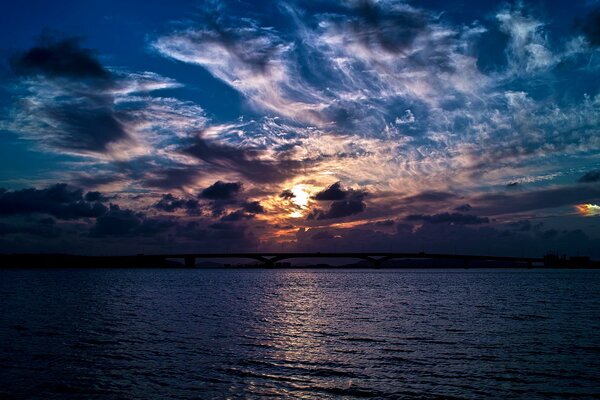 The moon shines through the clouds over the lake