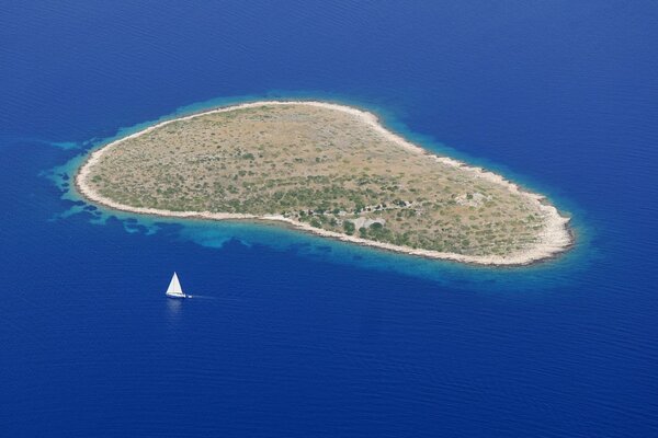 An island in the middle of the ocean. Yacht off the island