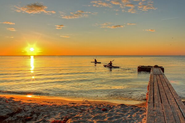 Persone in mare su barche al tramonto