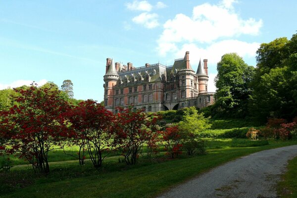 An ancient castle surrounded by lush park greenery on a sunny day