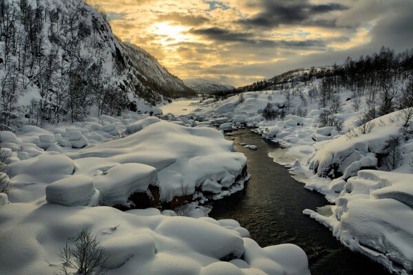 El río fluye a través de las montañas y la nieve