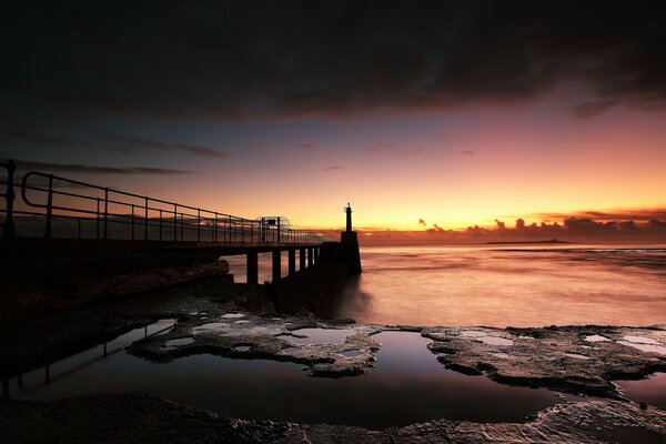 Puente en la costa del lago. Atardecer