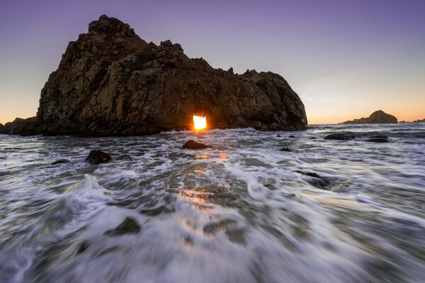 A rock in the sea and a frothy sunset