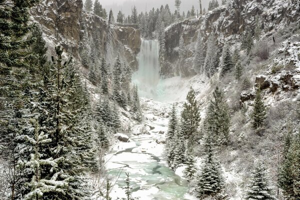 A river with a waterfall along the snowy cliffs