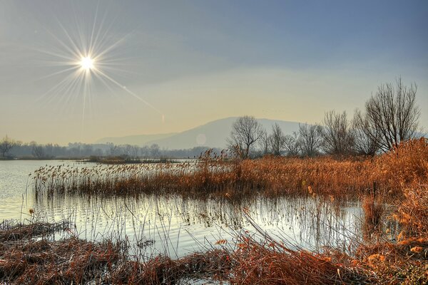 The autumn sun sets behind the river