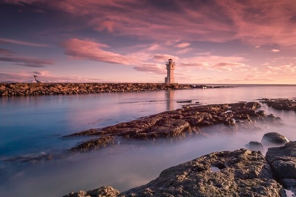 Leuchtturm im Meer mit schönem Sonnenuntergang