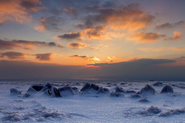 Piedras cubiertas de nieve, en el fondo del cielo al atardecer