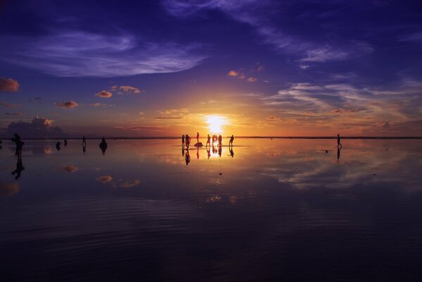 People in the distance at sunset by the sea