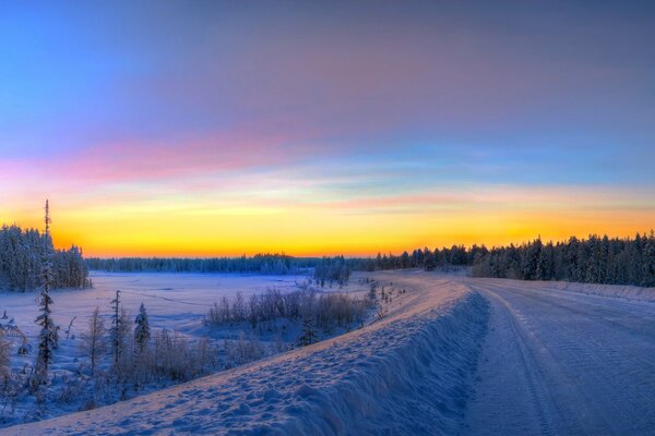 Winter road through the forest. Sunrise