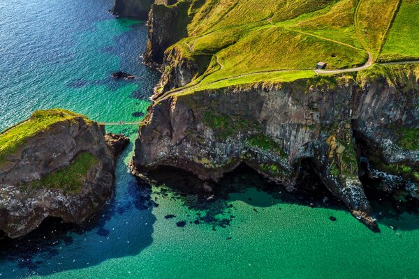 Rope bridge between rocks on the background of the sea