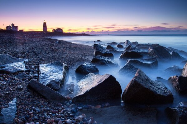 Stones on the background of the lighthouse and the sea