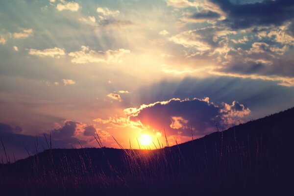 El sol se pone en las nubes sobre las colinas