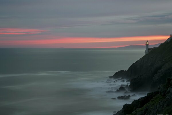 Faro al atardecer. Rocas y mar