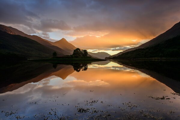 Herbst Sonnenuntergang in Schottland. Der Himmel spiegelt sich im Wasser und in den Bergen wider