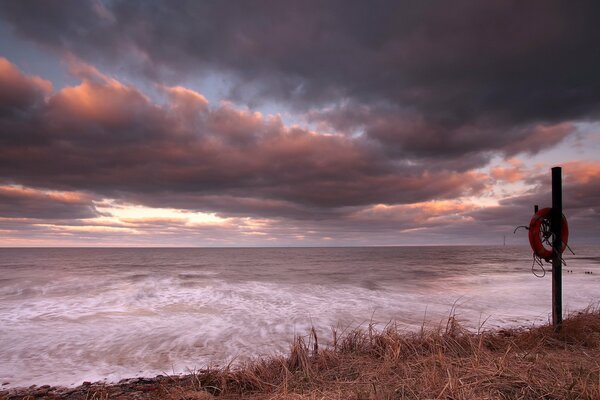 The seashore at sunset with a pillar and a rescue circle