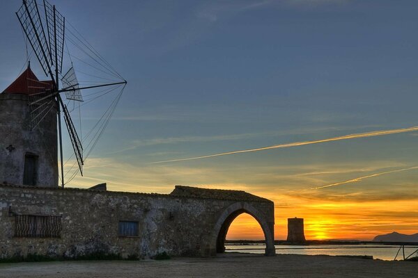 Windmill on the background of order and water. Italy