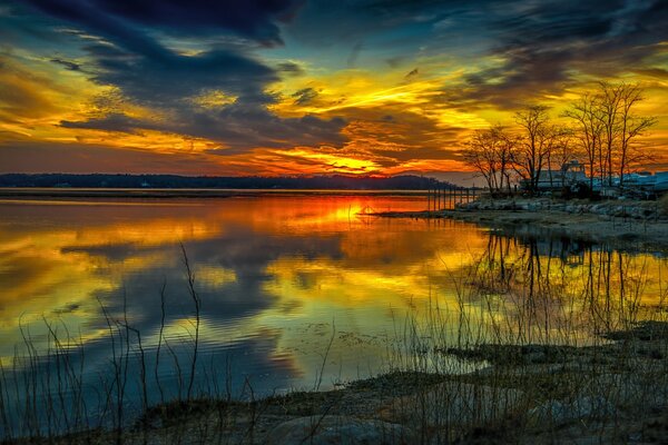 Sonnenuntergang glühen über dem See und den Bäumen