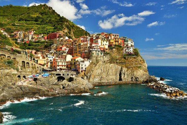 Manarolla, Italia, Cinque Terre. Case vicino al mare sullo sfondo delle montagne