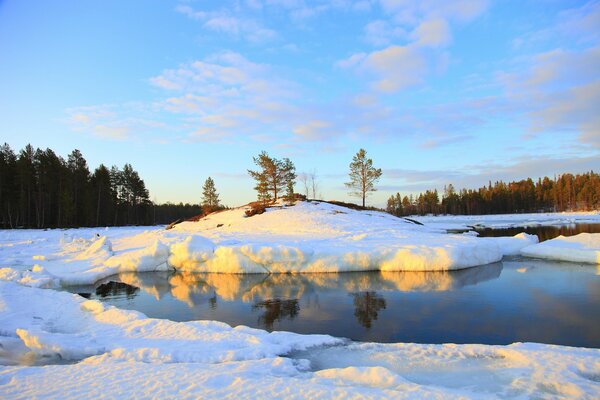 Fluss und Winterwald vor dem Hintergrund des blauen Himmels