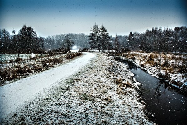 Strada invernale attraverso la foresta lungo il fossato