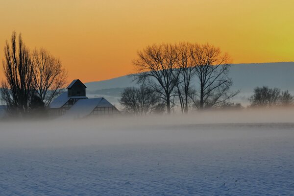 A snow-covered plain and a house under an orange sky