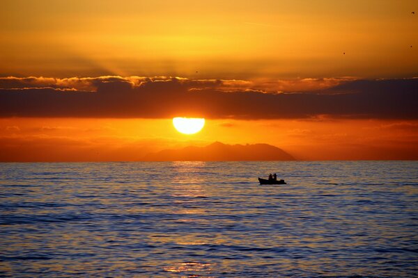 Two in a boat at sea at sunset