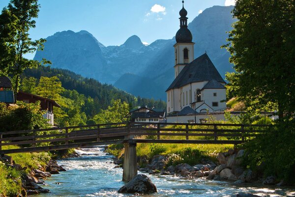 Pont sur la rivière parmi les arbres, les montagnes, l église