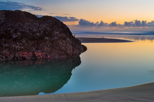 Puesta de sol en la costa contra un acantilado