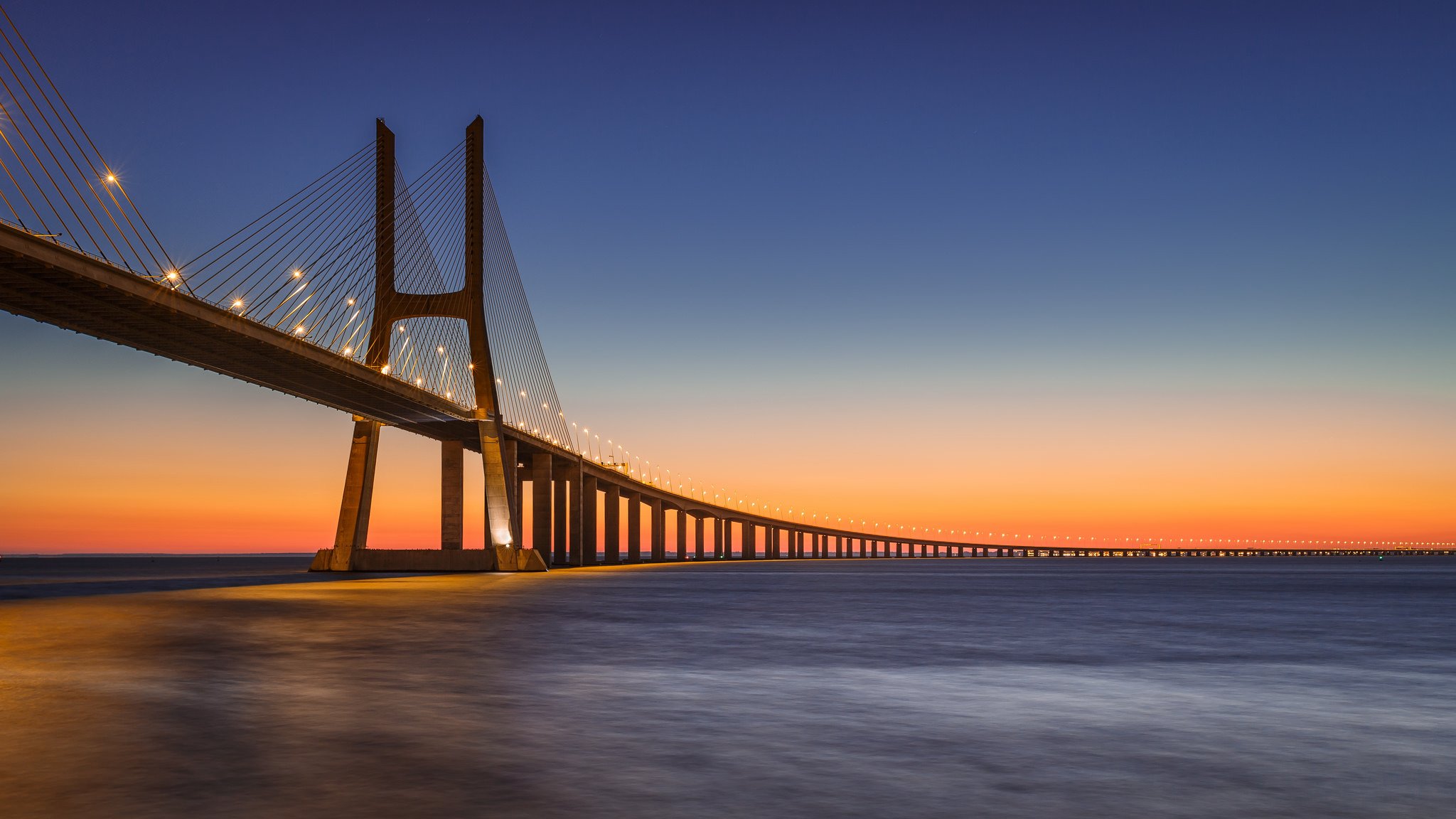 portugal lissabon fluss tajo tejo brücke vasco da gama lichter beleuchtung abend orange sonnenuntergang blau himmel