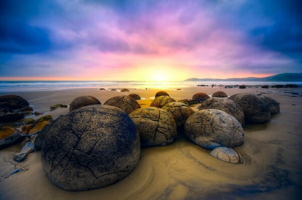 Boulders lying on the sand meet the sunrise