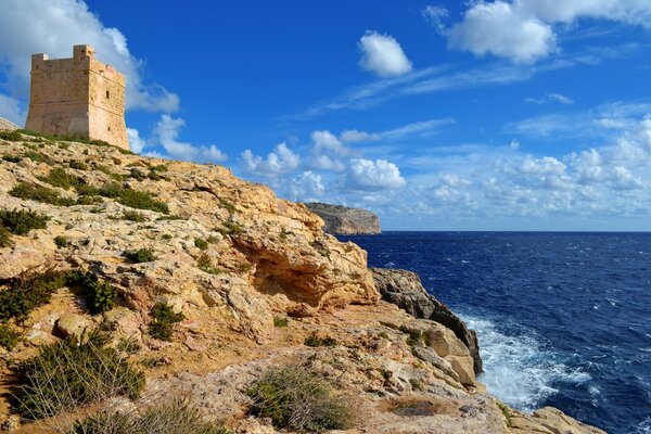 Une forteresse solitaire se dresse sur un rivage argileux au-dessus d une mer d un bleu profond