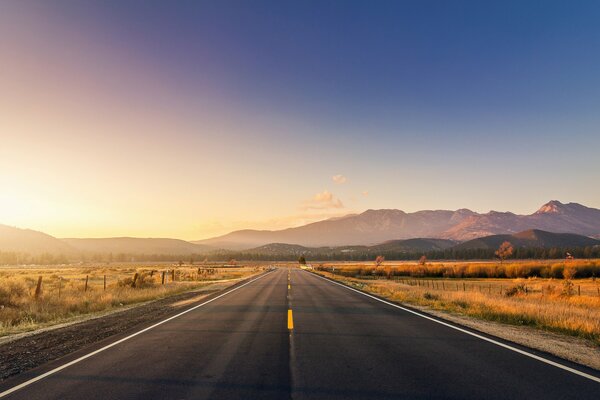 The road on the background of sunset goes into the distance