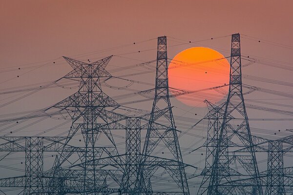 Stromleitung vor dem Hintergrund eines leuchtend roten Sonnenuntergangs