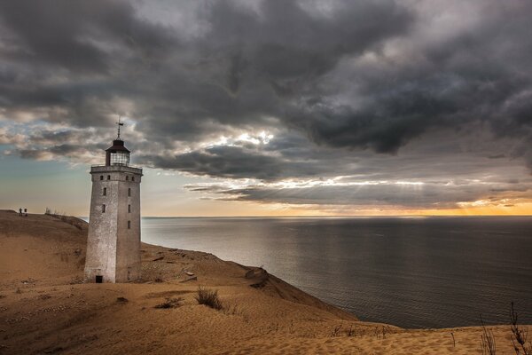 Un phare solitaire se dresse sur la plage de sable de la mer