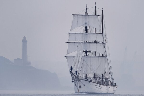 Segelboot bei Nebel im Meer in der Nähe des Leuchtturms